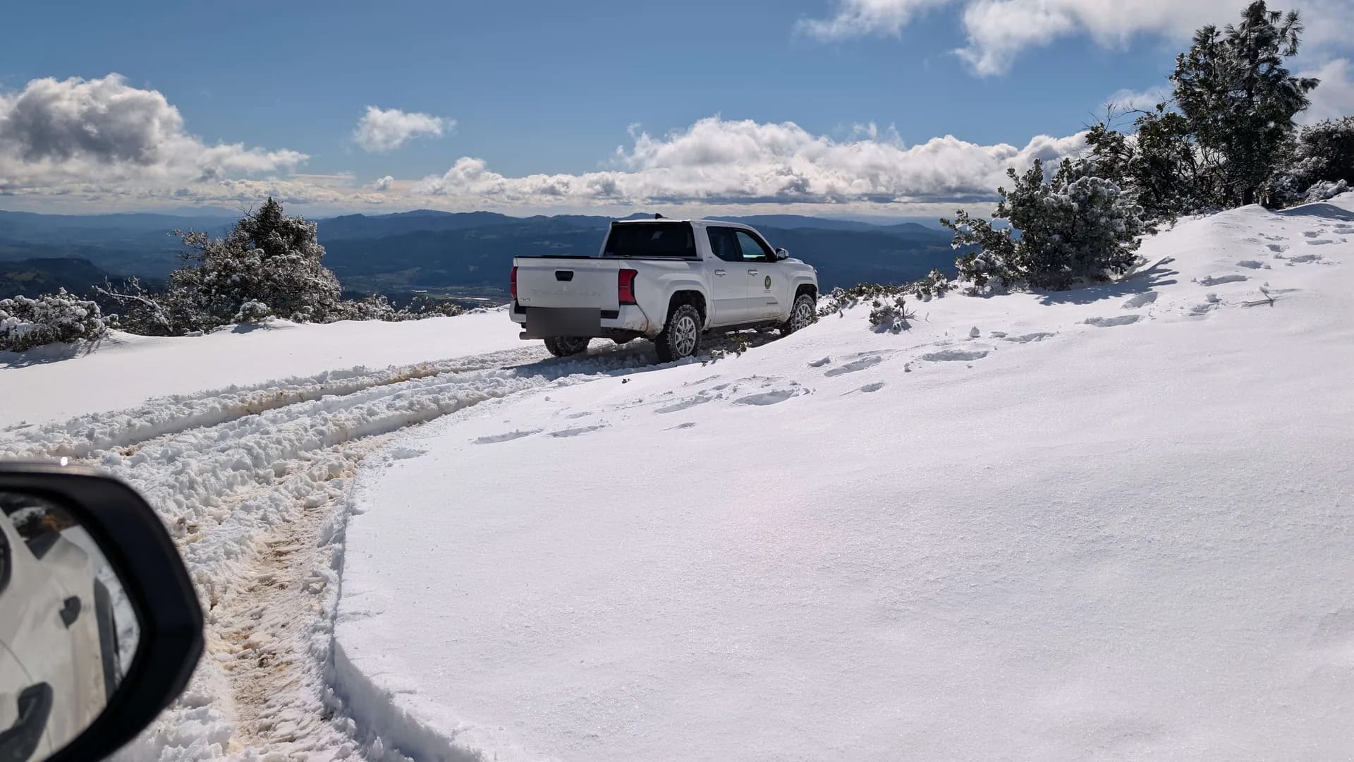A Trellis pickup parked on a snow-covered ridge with a sweeping Mayacamas vista under big-sky weather.